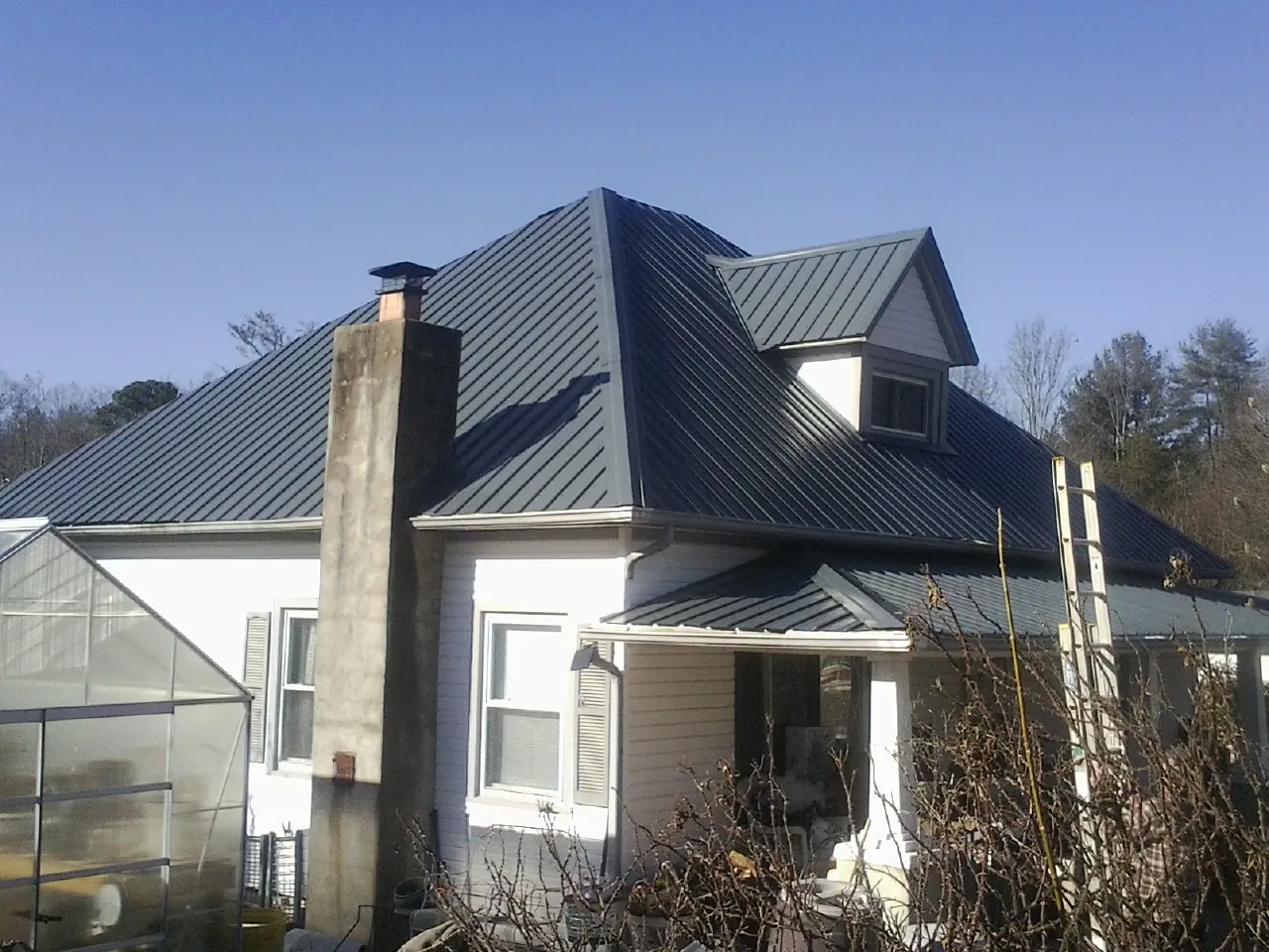 Dark blue standing seam metal roof on a white farmhouse with dormer — Slate & Tile Roof Repair by Roofing Brothers in Vacaville