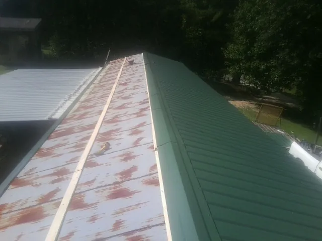 Old rusted panels beside newly installed green metal roofing — Wind Damage Roof Repair by Roofing Brothers in Vacaville