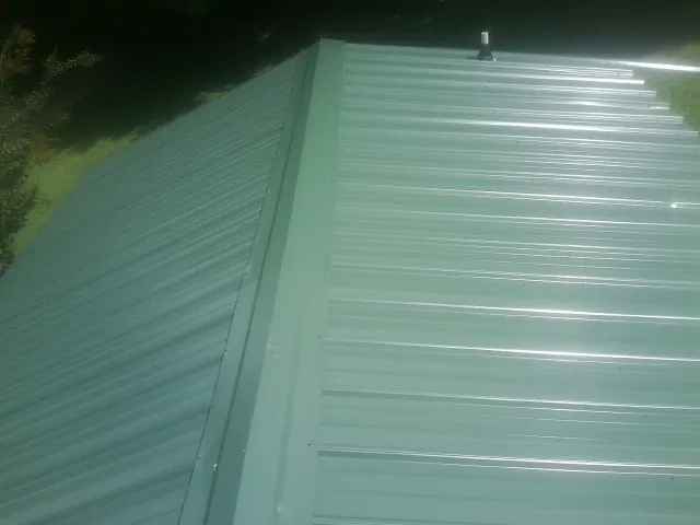 New green metal panels meeting at the ridge of a roof — Flat Roof Repair work by our crew in Vacaville