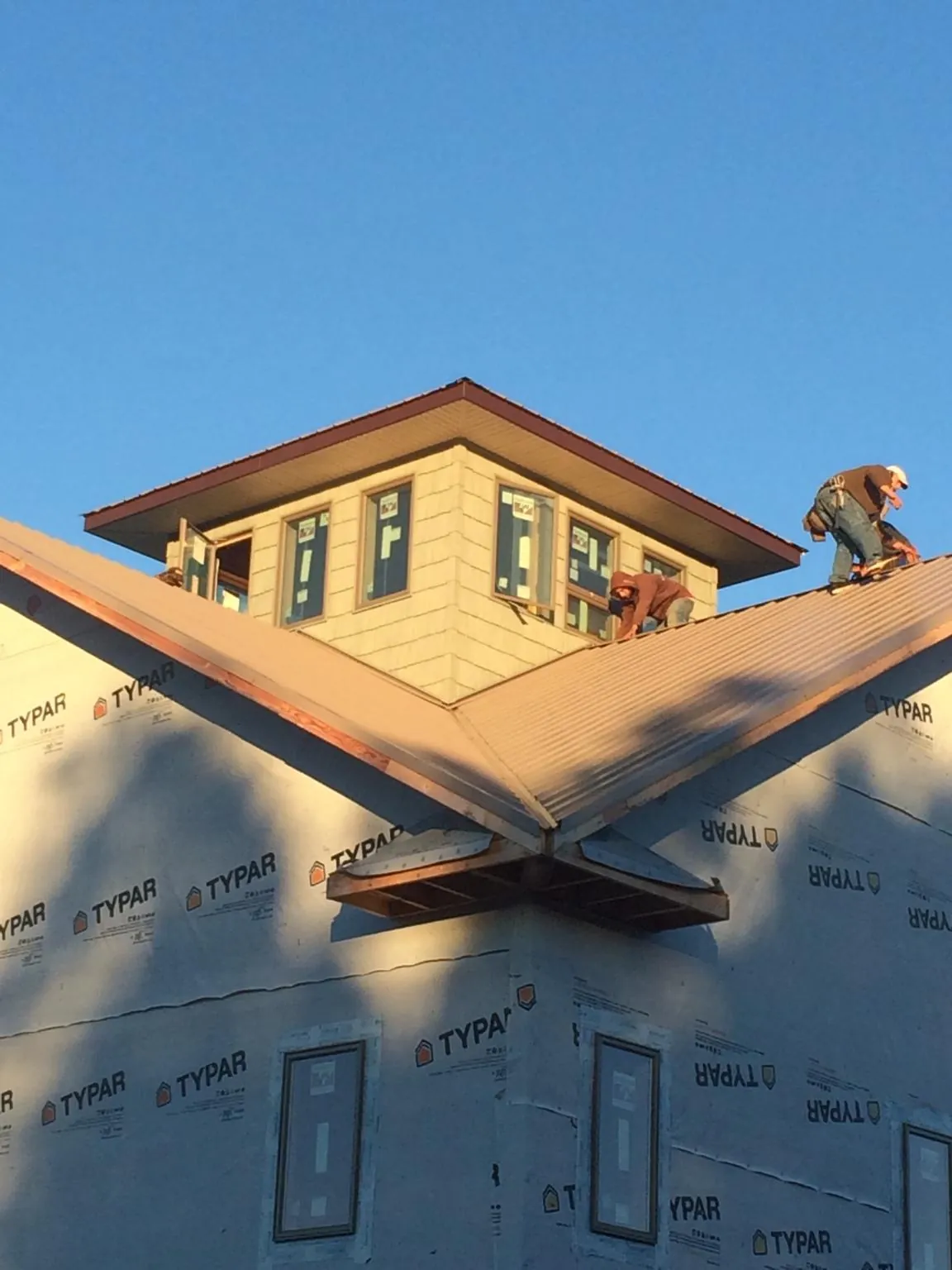 Roofers working around a rooftop cupola on a new metal roof at sunset — Roof Waterproofing in Vacaville by Roofing Brothers